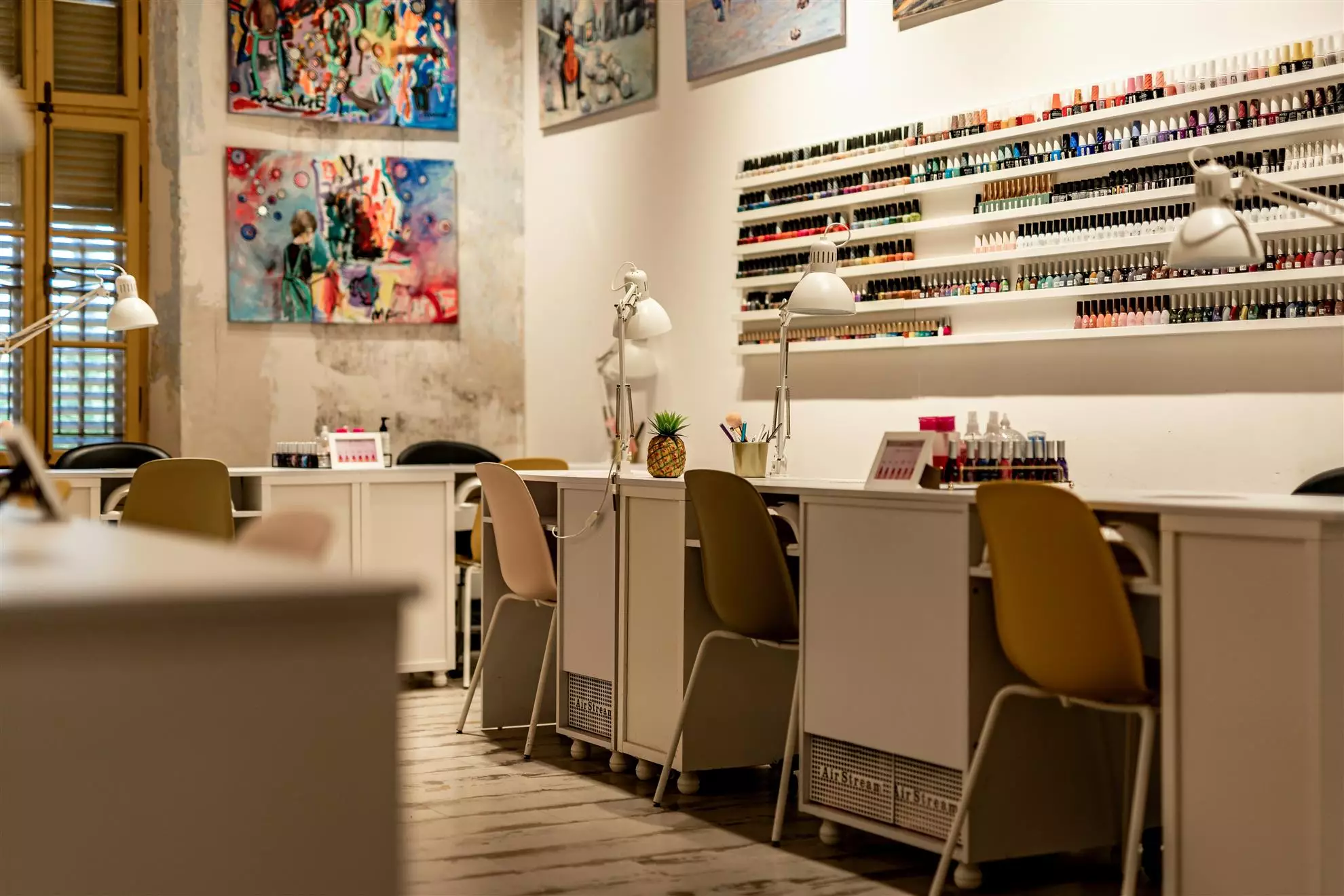 Interno di un salone di unghie con diverse postazioni di lavoro e sedute per i clienti