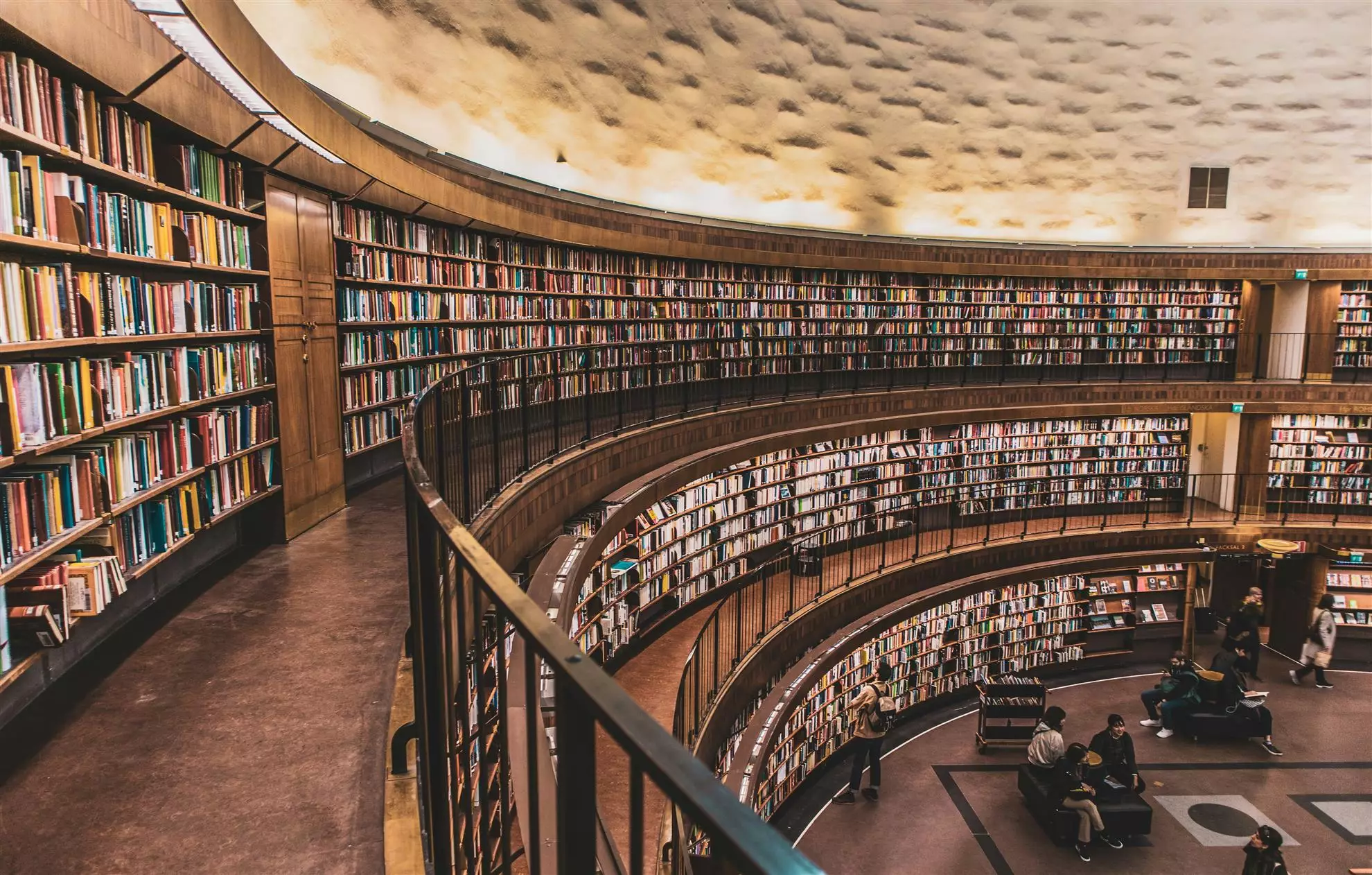 Interno di una vasta biblioteca, caratterizzata da scaffali colmi di libri di varie dimensioni e colori.