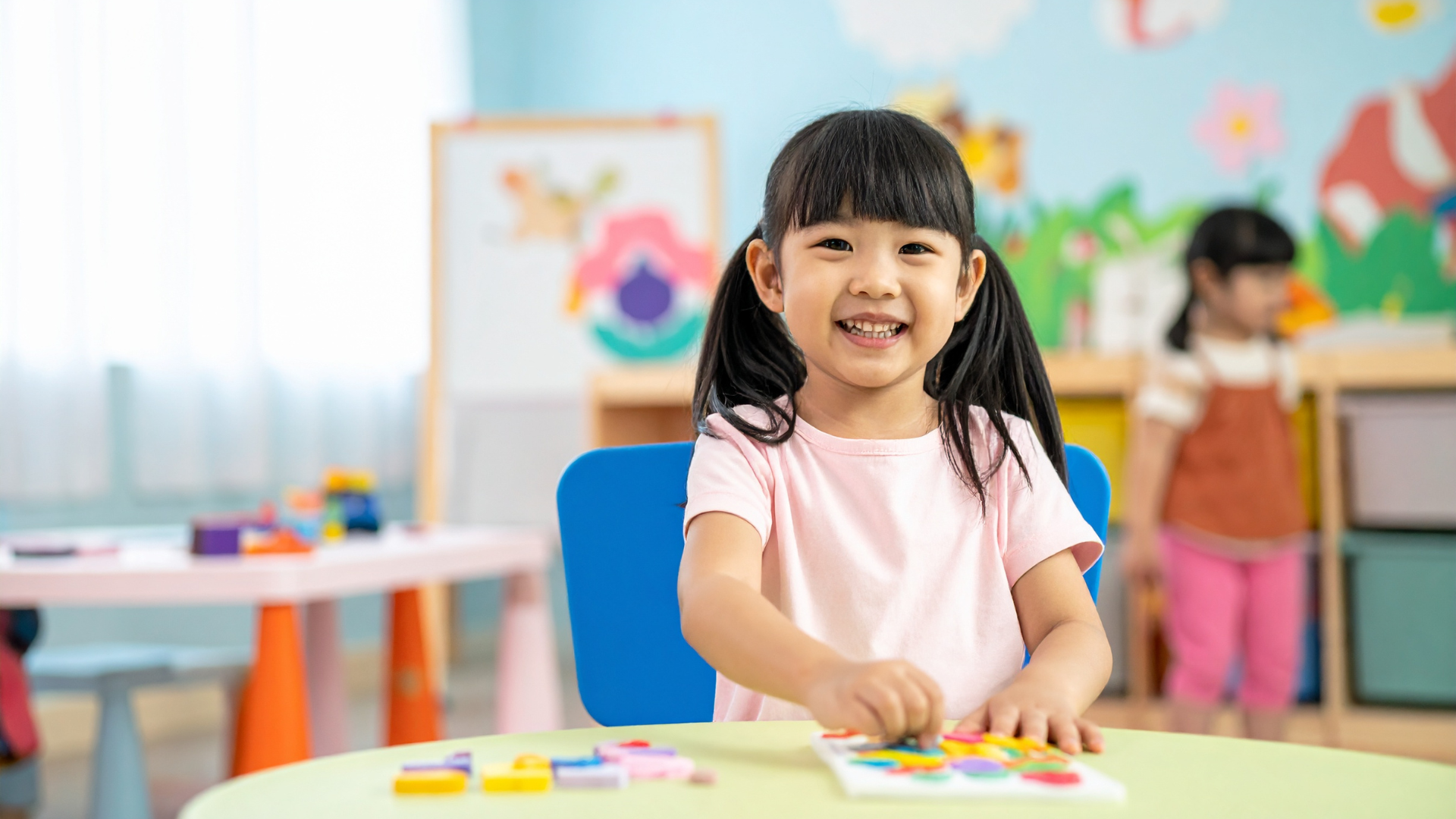 Una bambina in una ludoteca seduta a un tavolo, intenta a giocare con blocchi colorati disposti davanti a lei.