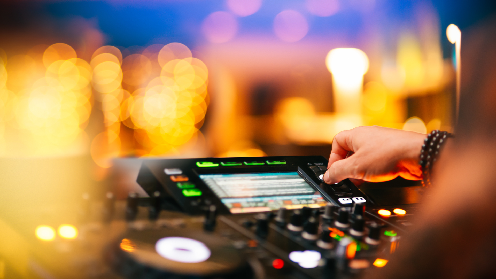 DJ che mixa musica a una festa, con attrezzatura audio e luci colorate sullo sfondo. 