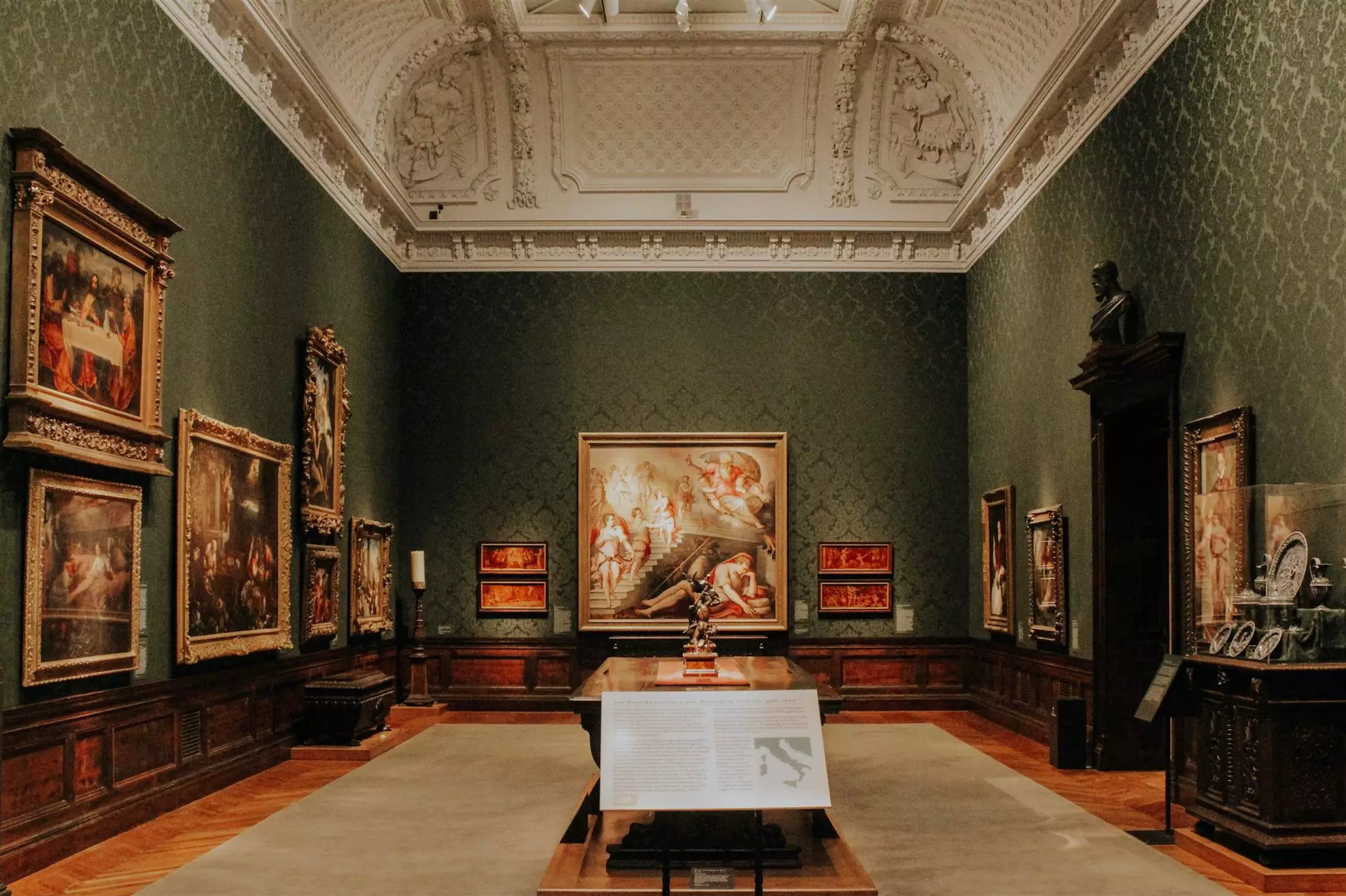 Interno di una vasta sala da museo adornata da molte opere d'arte, evidenziando la ricchezza visiva dell'ambiente.