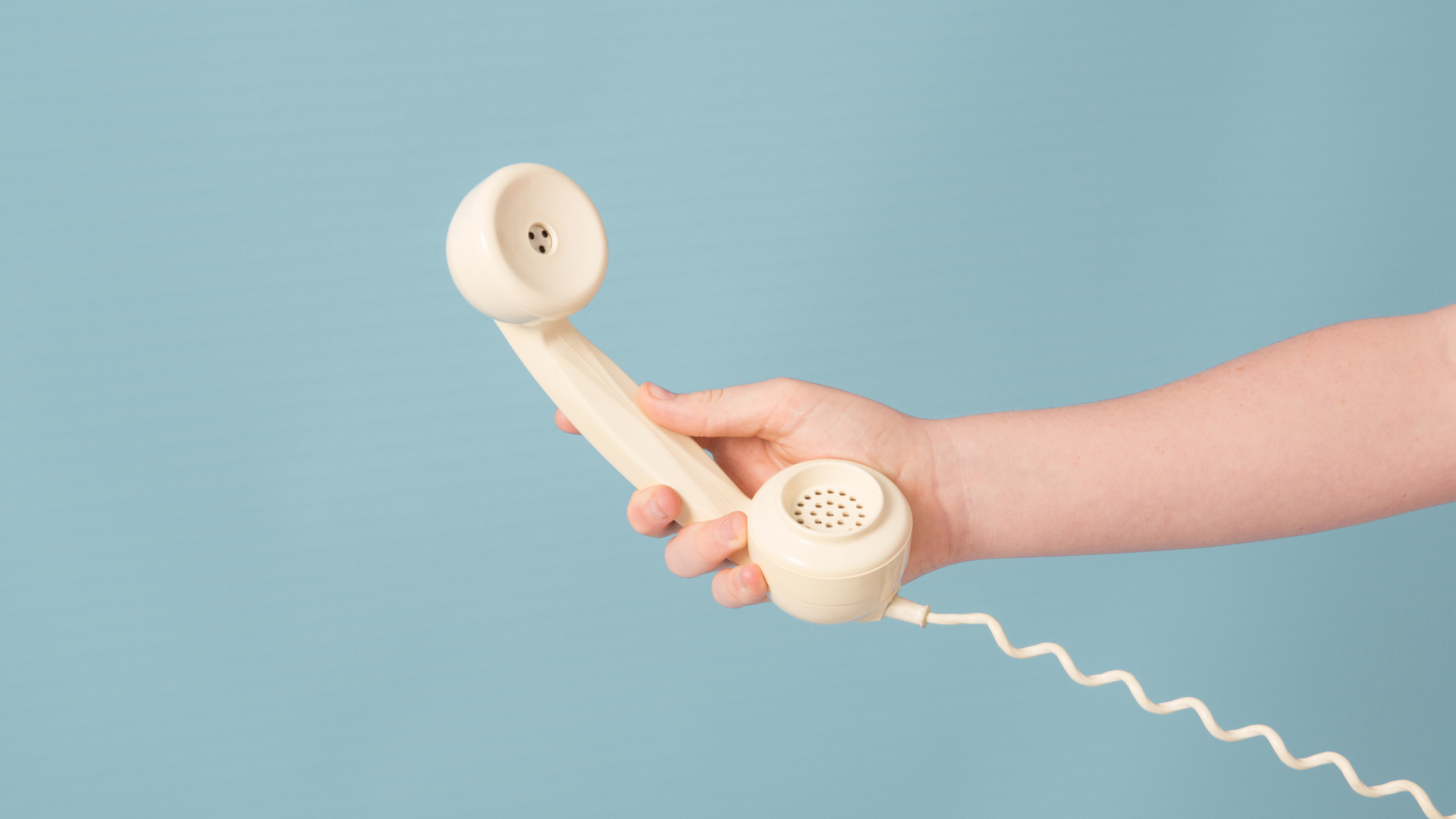 Mano che afferra un telefono, su uno sfondo di colore blu.