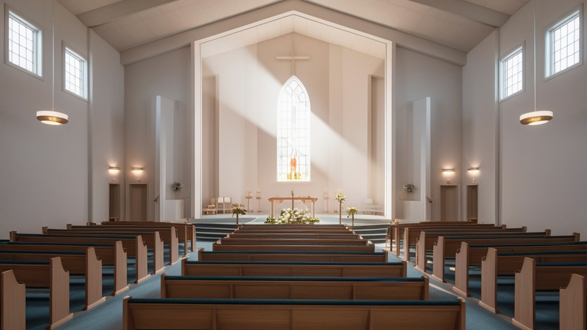 Interno di una chiesa con panche in legno e una grande finestra che illumina lo spazio. 