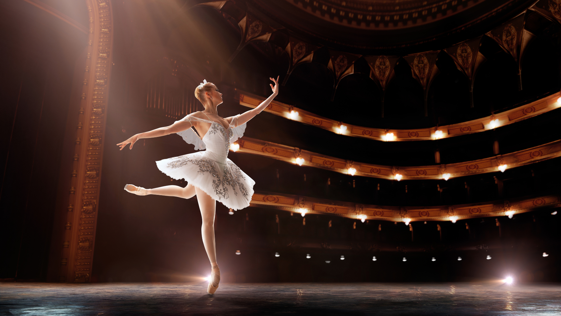 Una ballerina in abito bianco danza elegantemente sul palcoscenico, catturando l'attenzione del pubblico.